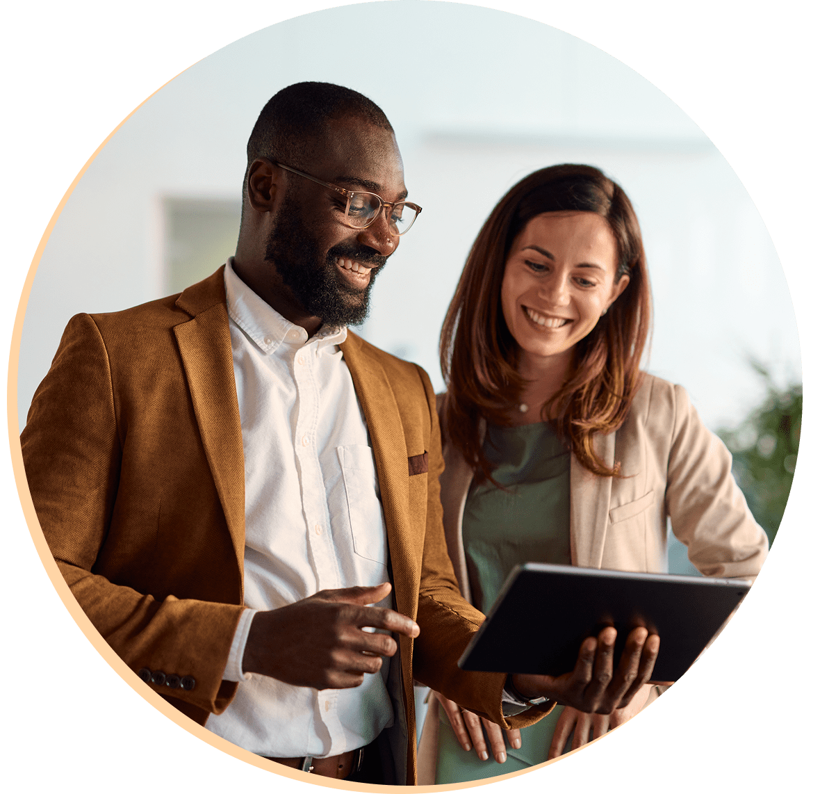Two colleagues smiling while looking at tablet.