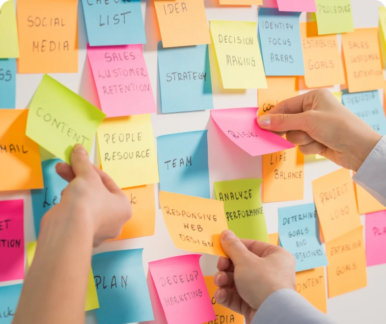 Hands arranging colorful sticky notes on board.